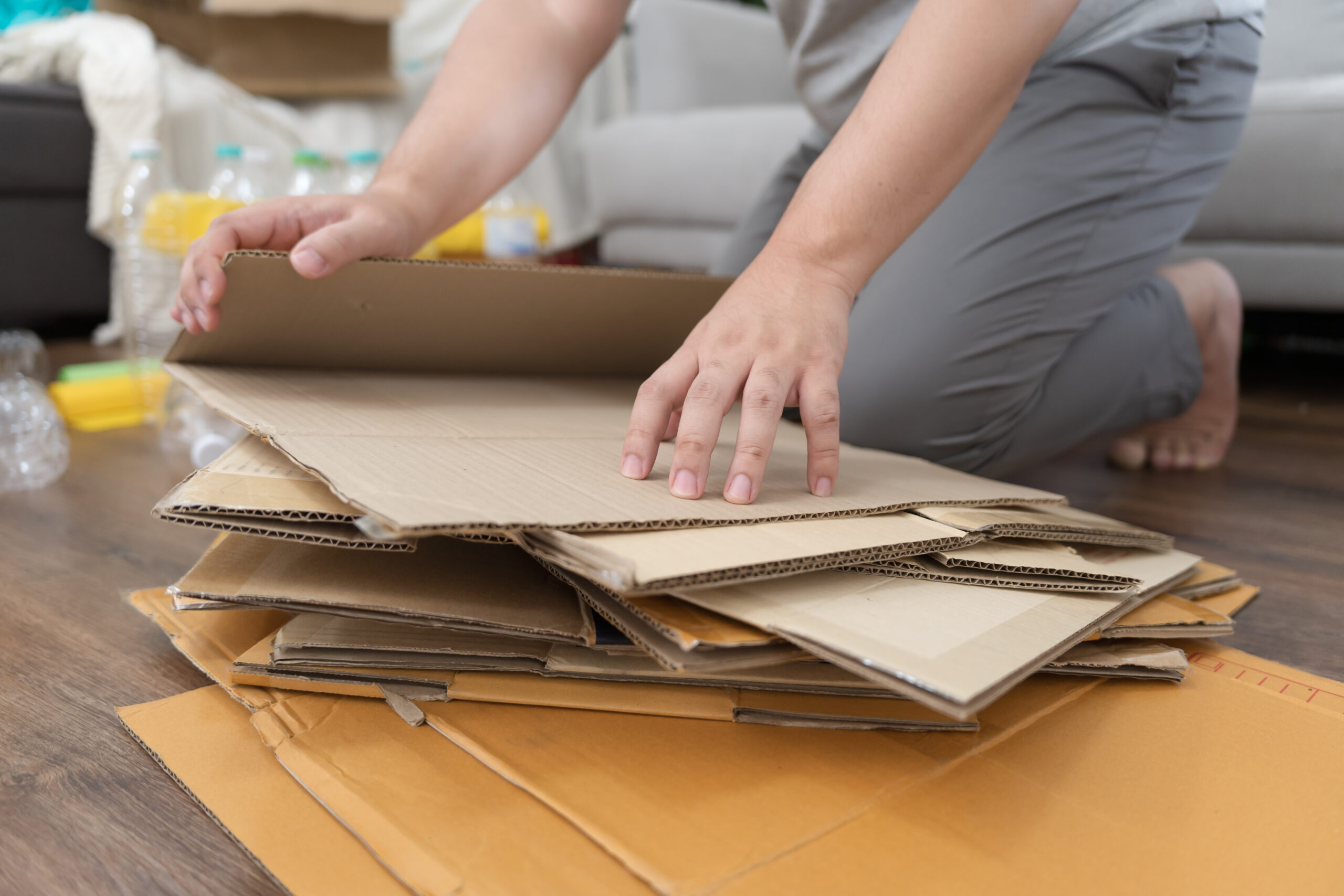 hands stacking flattened boxes getting them ready for recycling