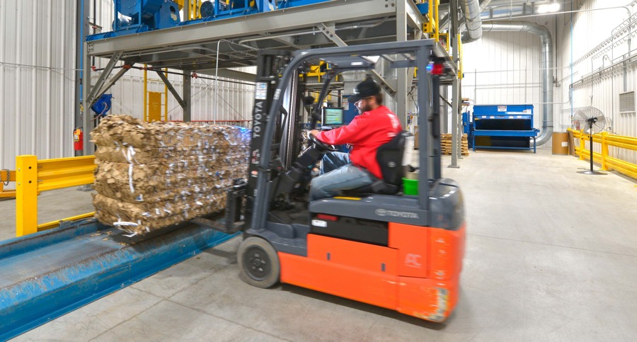 A forklift driver loads corrugated packaging for recycling