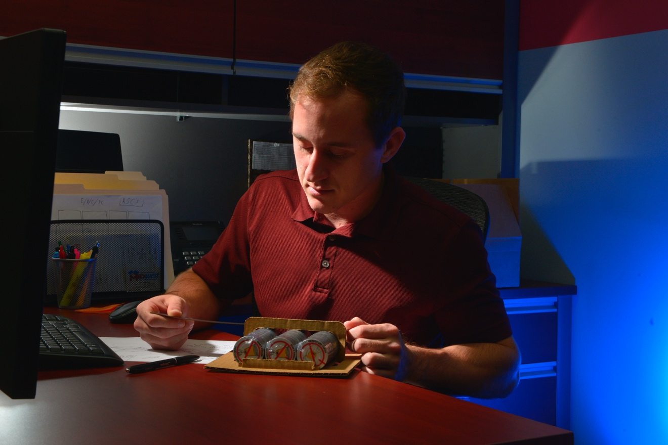 A packaging designer measures a package mockup for precise product fitment.